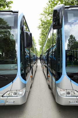 two charter buses parked next to each other, with silver and blue trim