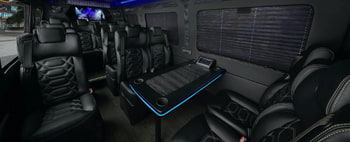 a charter bus interior with a table and black leather seats